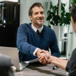 happy-financial-consultant-greeting-his-clients-while-meeting-them-their-home-me-are-shaking-hands